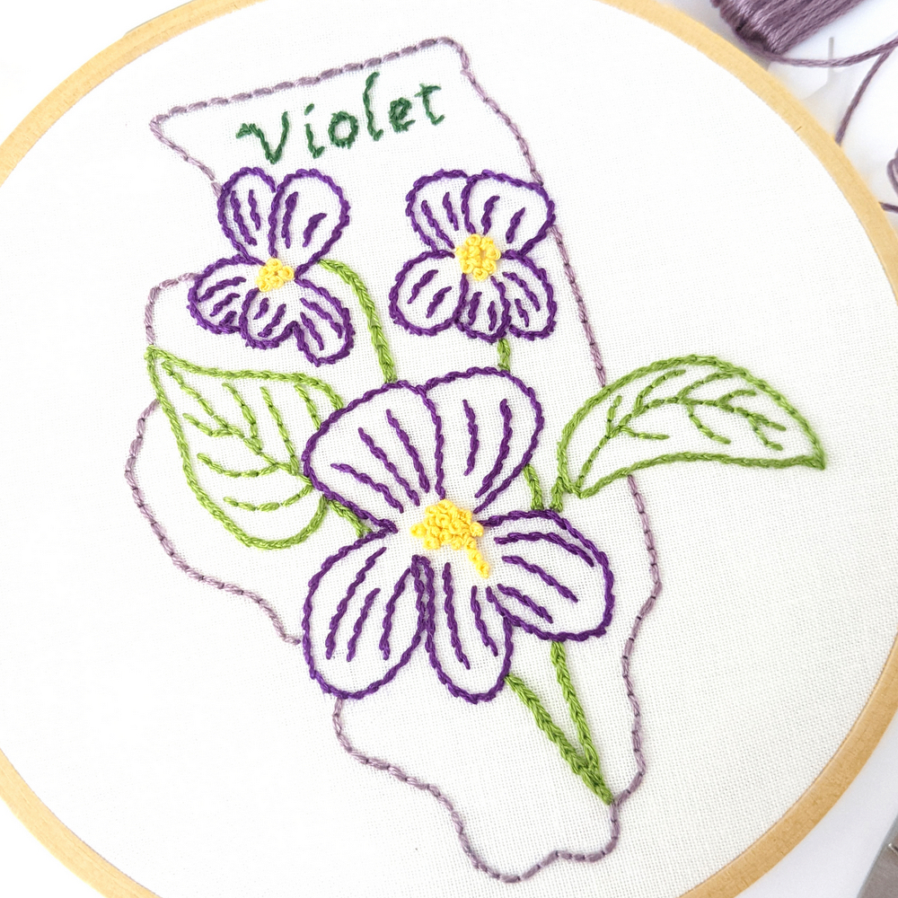 Violet flowers stitched on white fabric inside the Illinois state outline.