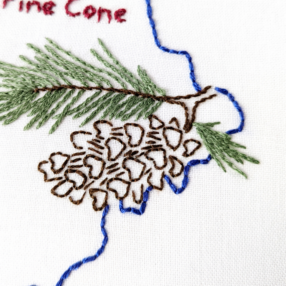 Pine cone stitched on white fabric