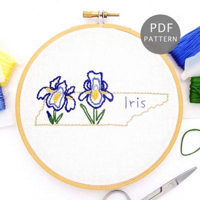 Purple Iris stitched on white fabric inside the Tennessee state outline.