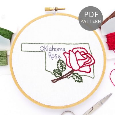 Large red rose stitched on white fabric inside the Oklahoma state outline.