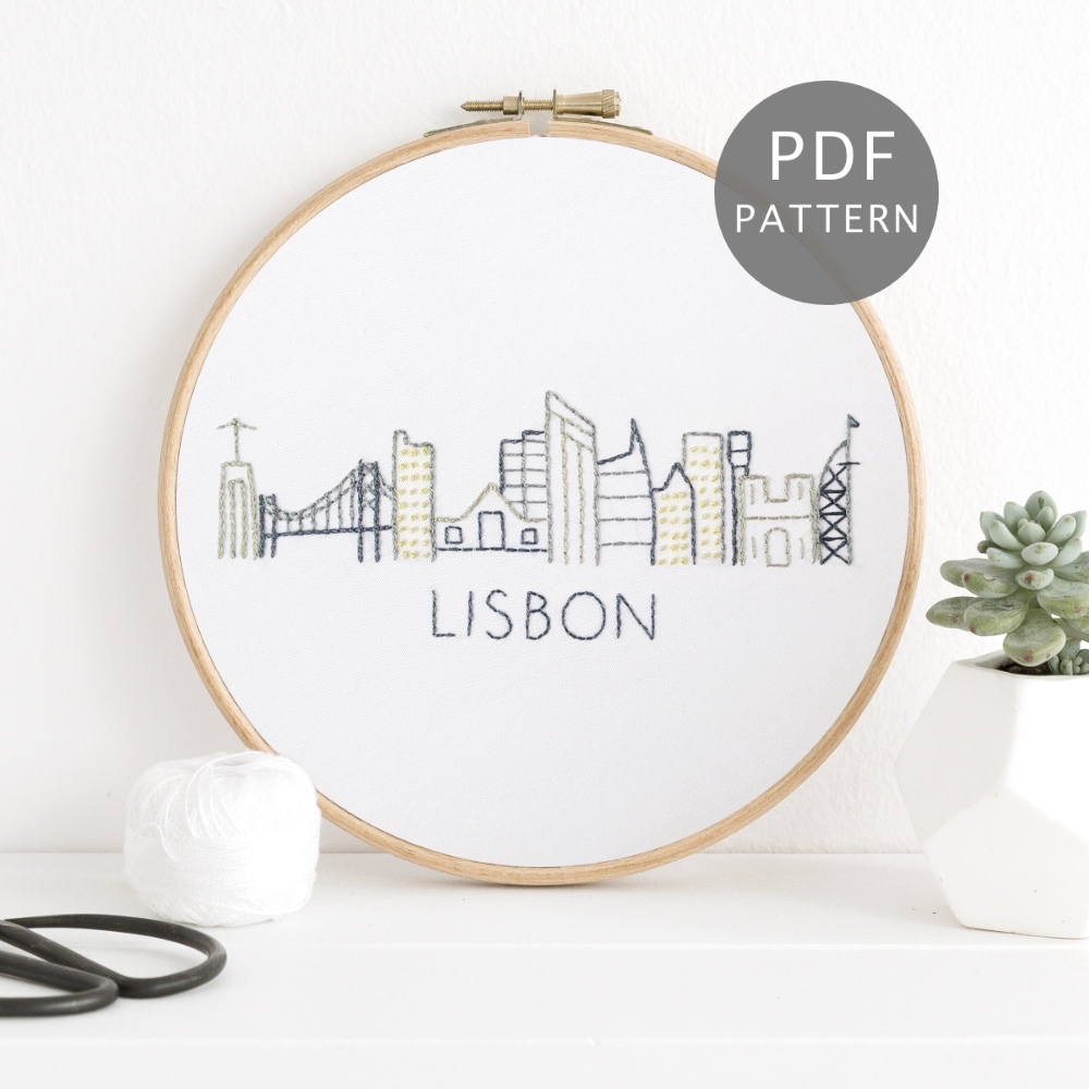 Lisbon city skyline stitched on white fabric inside a wooden hoop.