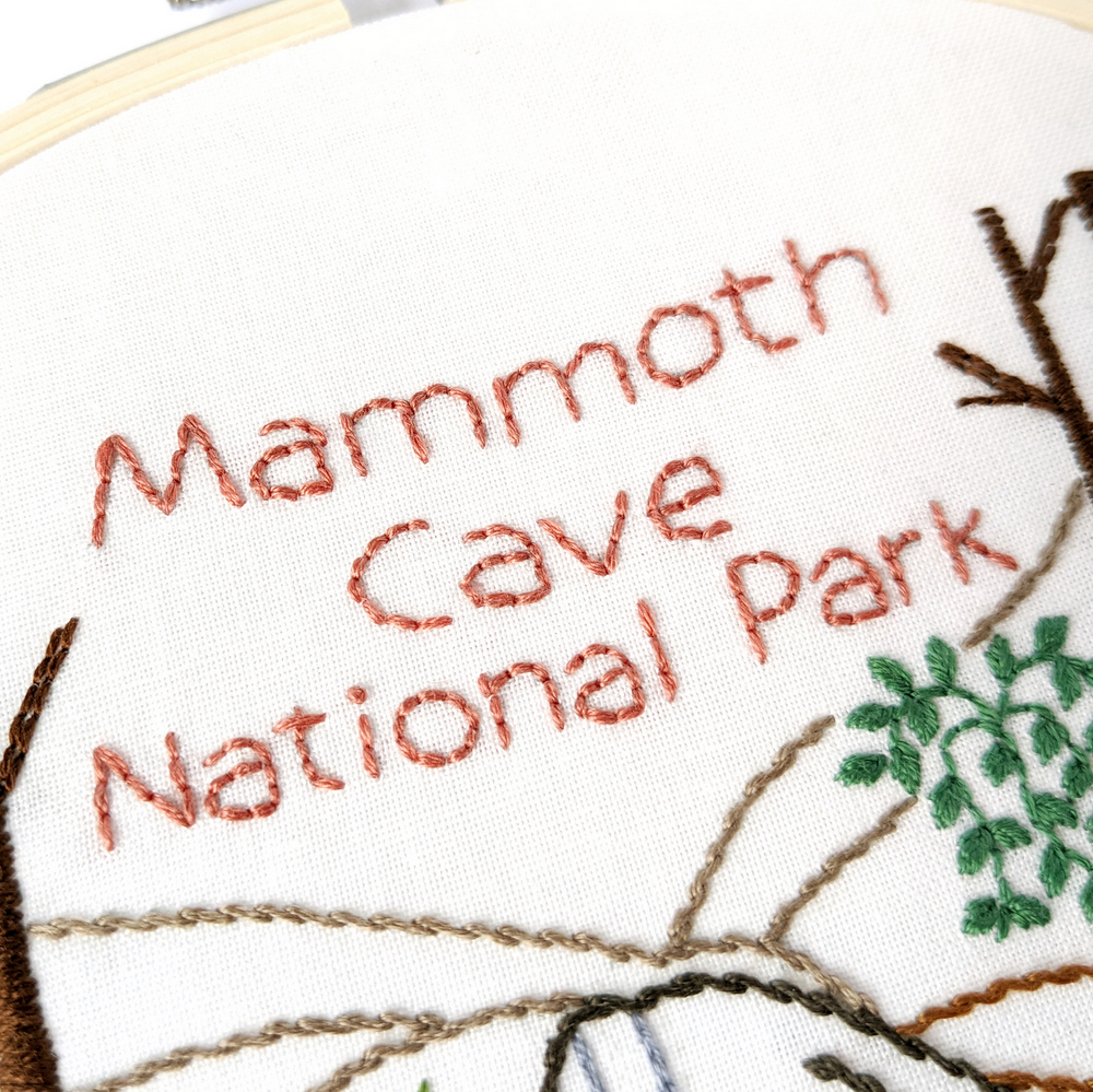 The words Mammoth Cave National Park stitched in dark pink on white fabric.
